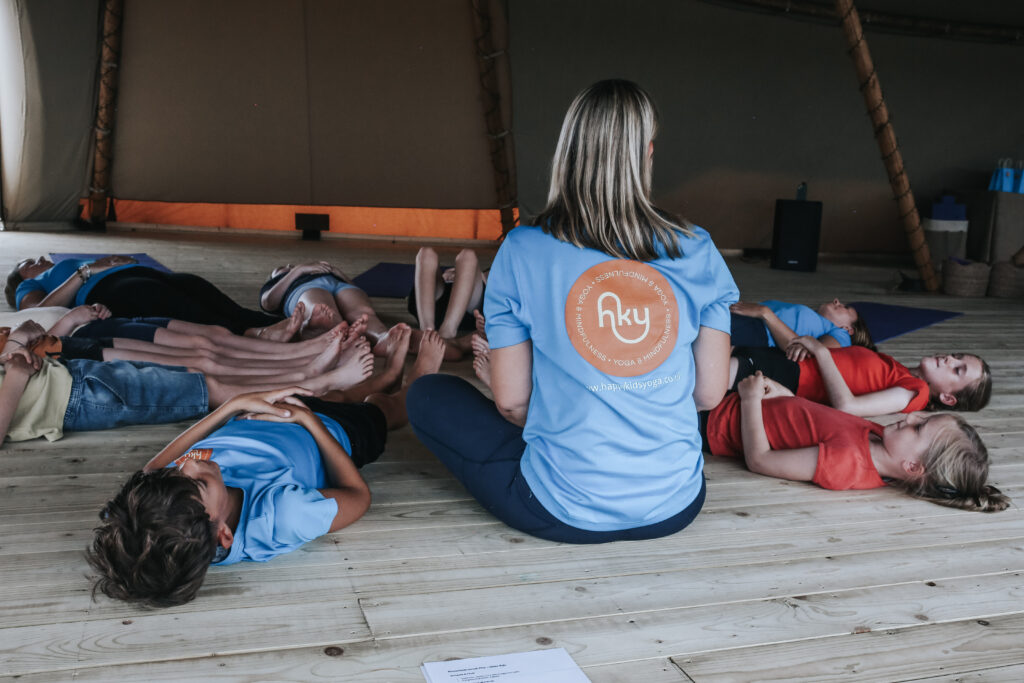 Happy Kids Yoga teacher leading a relaxation exercise with children lying on the floor