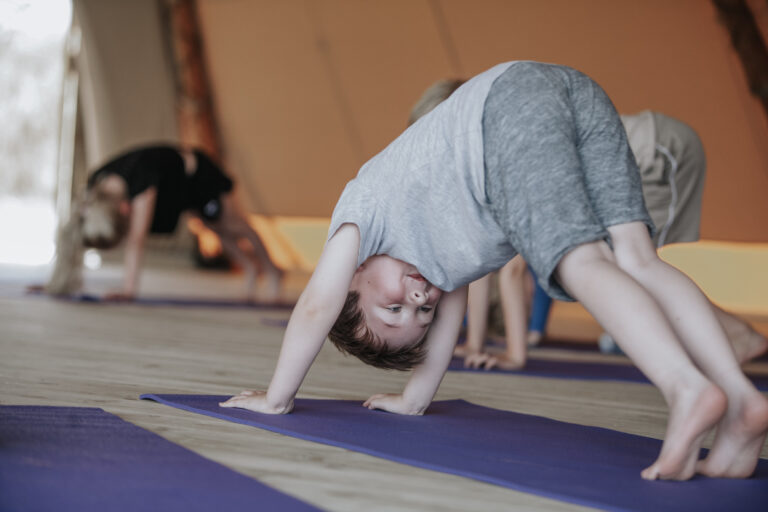 A boy in downward dog on a purple mat