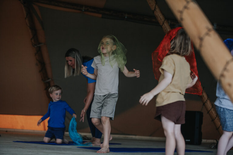 Children dancing with scarves while a Happy Kids Yoga teacher joins in