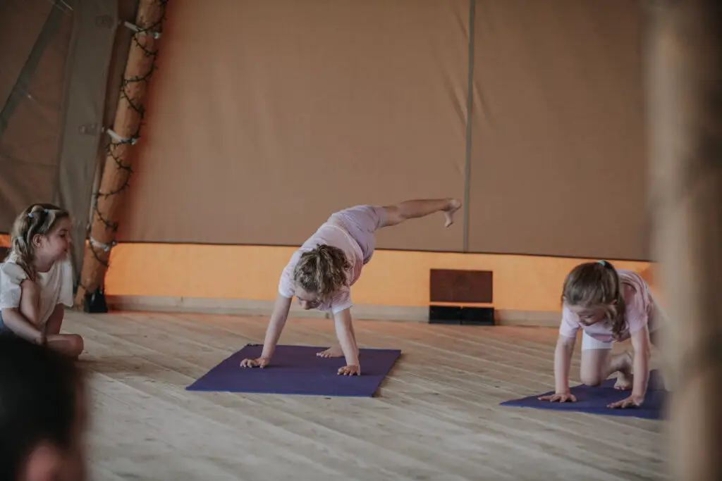 Girl lifting one leg in a downward dog pose during a Happy Kids Yoga class
