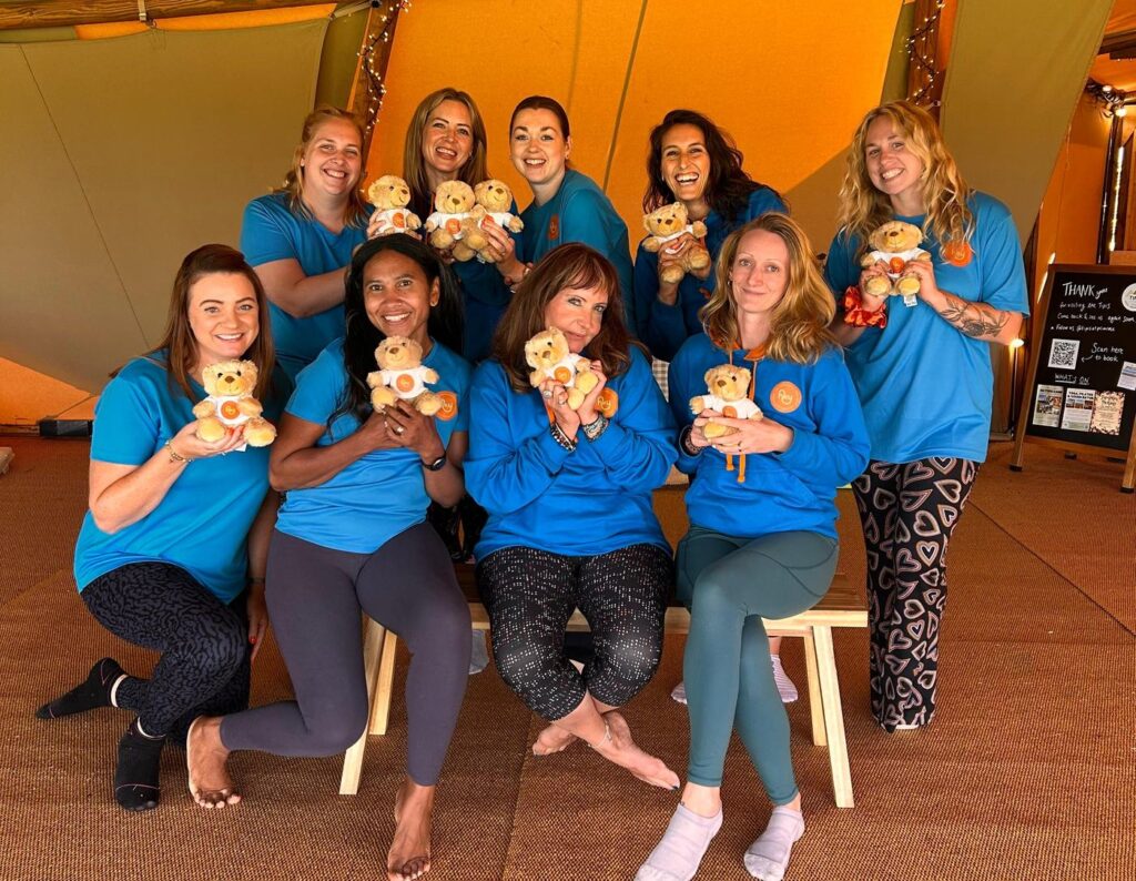 The Happy Kids Yoga franchisee family holding teddy bears in the tipi at our first Big Team Get Together