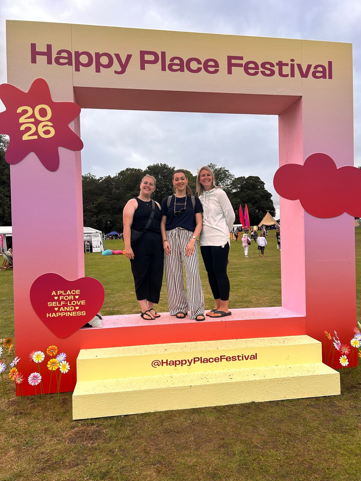 Three Happy Kids Yoga franchisees standing in the Happy Place Festival 2026 photo frame