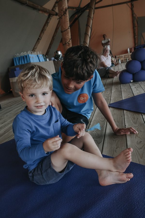 A boy stretching with help from a Happy Kids Yoga teacher