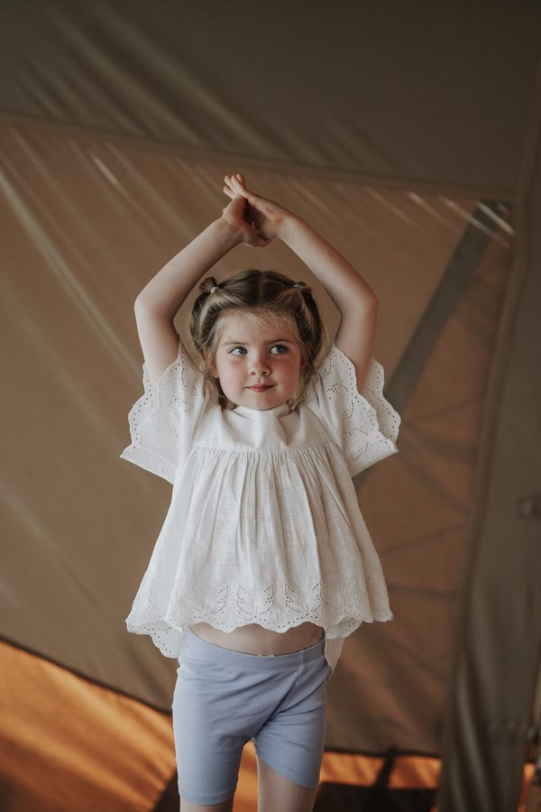 A little girl with her hands together above her head