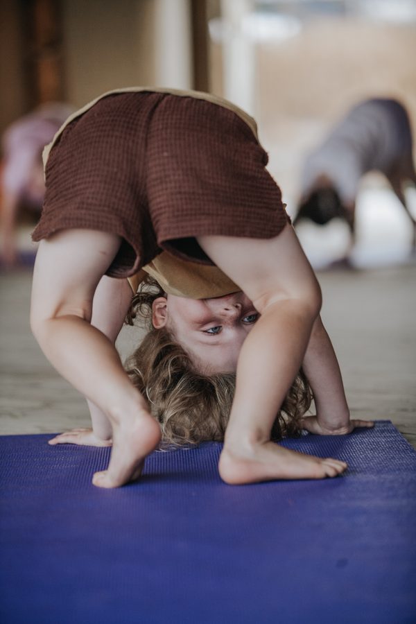 A child looking through their legs in a forward fold