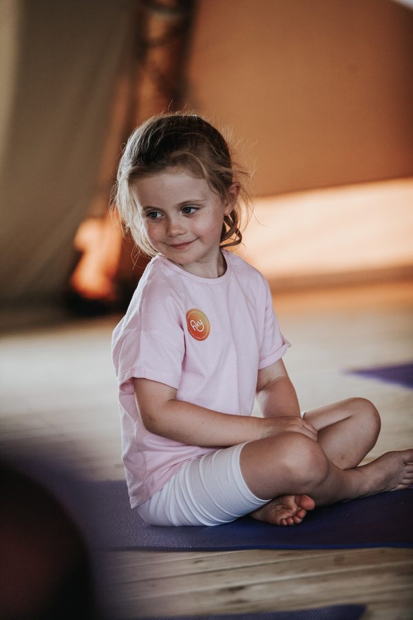 A smiling girl sitting cross legged on her mat