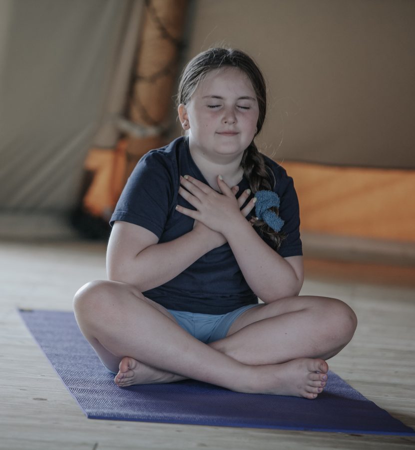 A girl sitting calmly with her hands on her heart