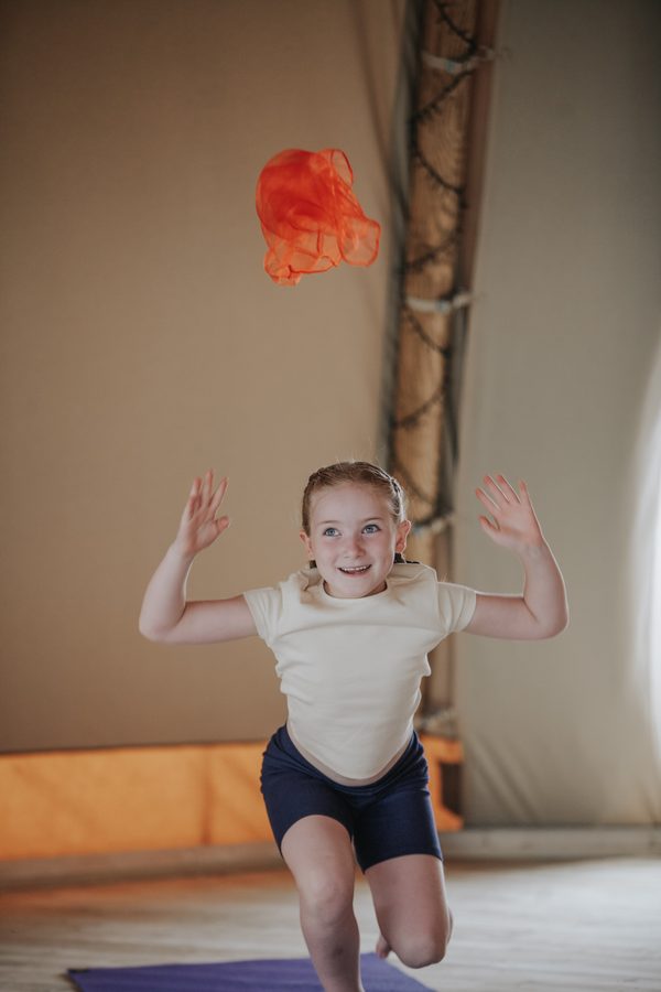 A girl with her arms out wide and a scarf flying above her