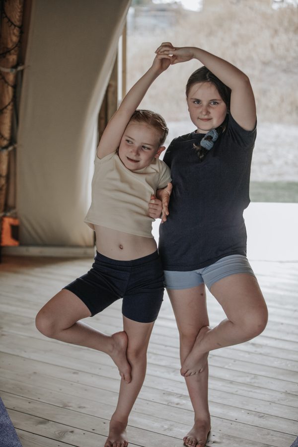Two girls side by side with their arms joined overhead
